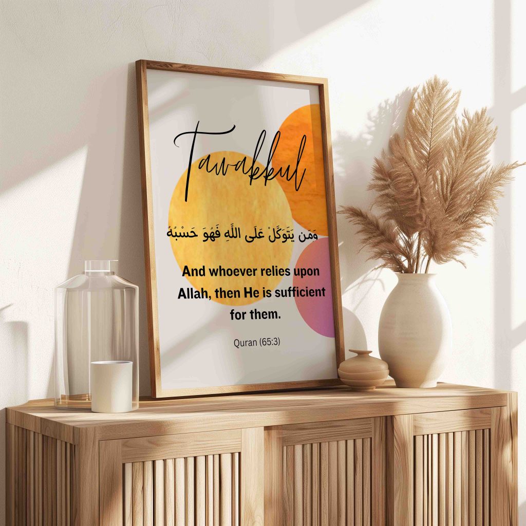 A reminder about Tawakkul and taking action: Tawakkul Arabic calligraphy print with warm yellow, orange and pink circles in a light wooden frame, leaning on a wooden sideboard beside a vase of pampas grass